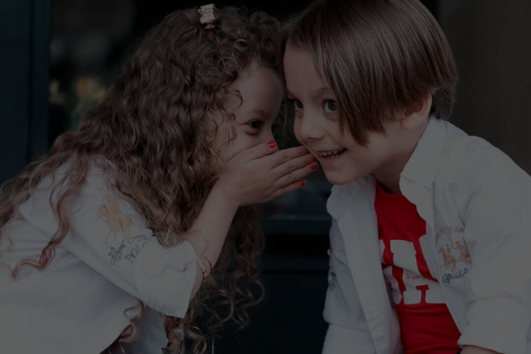Zwei Kinder die miteinander flüstern