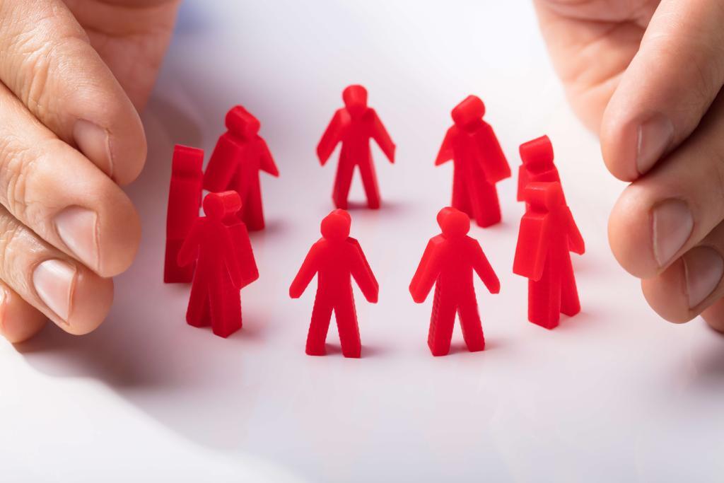 Hände, die rote, vereinfachte menschliche Figuren umgeben